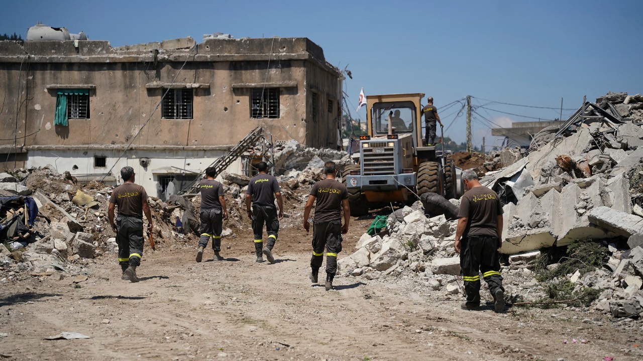 Lebanese civil defense workers walk behind a bulldozer as it removes the rubble from the main market place destroyed by the Israeli military in the southern Lebanese city of Nabatieh. /Abbas Fakih/AFP