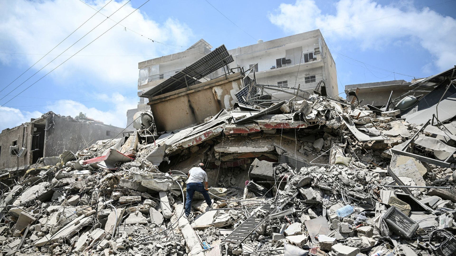 A man walks on the rubbles as he looks for items in a building hit in earlier Israeli military strikes on a neighbourhood in the southern Lebanese coastal city of Tyre on June 23. /Joseph Eid/AFP
