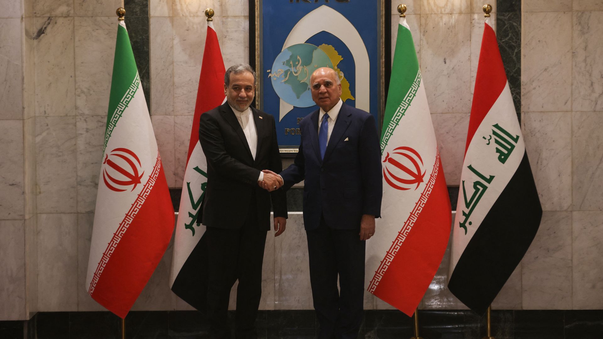 Iran and Iraq's foreign ministers Abbas Araghchi (L) and Fouad Hussein (R) shake hands in Baghdad, Iraq, on Sunday, June 28. AfP.