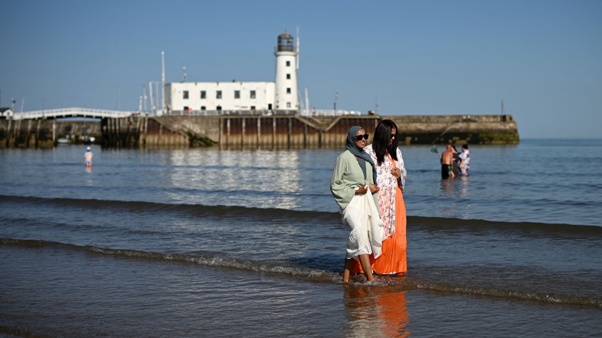 People walk in the sea on the beach during a heatwave, in Scarborough, northern England, in central England on June 2. 
/Oli Scarff/AFP