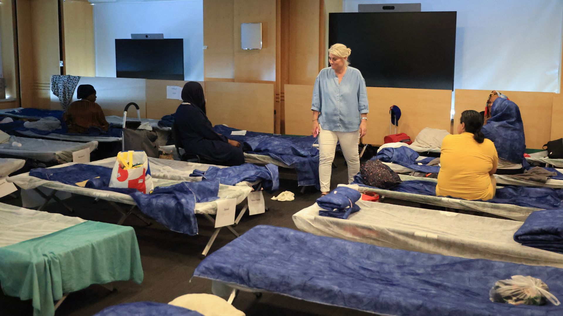 France's Health Minister Stephanie Rist walks amid camp bed as she visits an emergency shelter during the heatwave in Paris. /
Ludovic Marin/AFP
