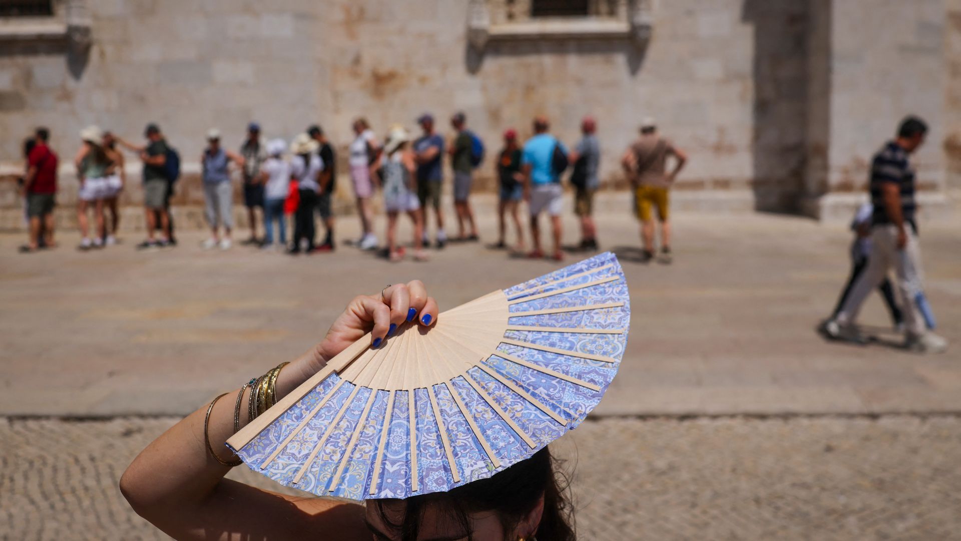 A woman shades her head with a fan in front of Jeronimos Monastery in Belem, during a heatwave in Lisbon on May 27. 
/Patricia De Melo Moreira/AFP
