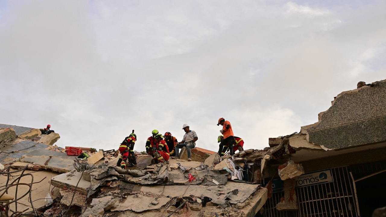 Rescuers stand atop the rubble of a collapsed building during search operation. /Martin Bernetti/AFP
