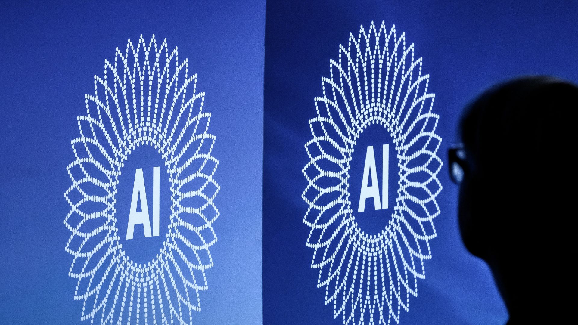 A person is silhouetted next to the logo of the first Global Dialogue on AI Governance, in Geneva. /Fabrice Coffrini/AFP