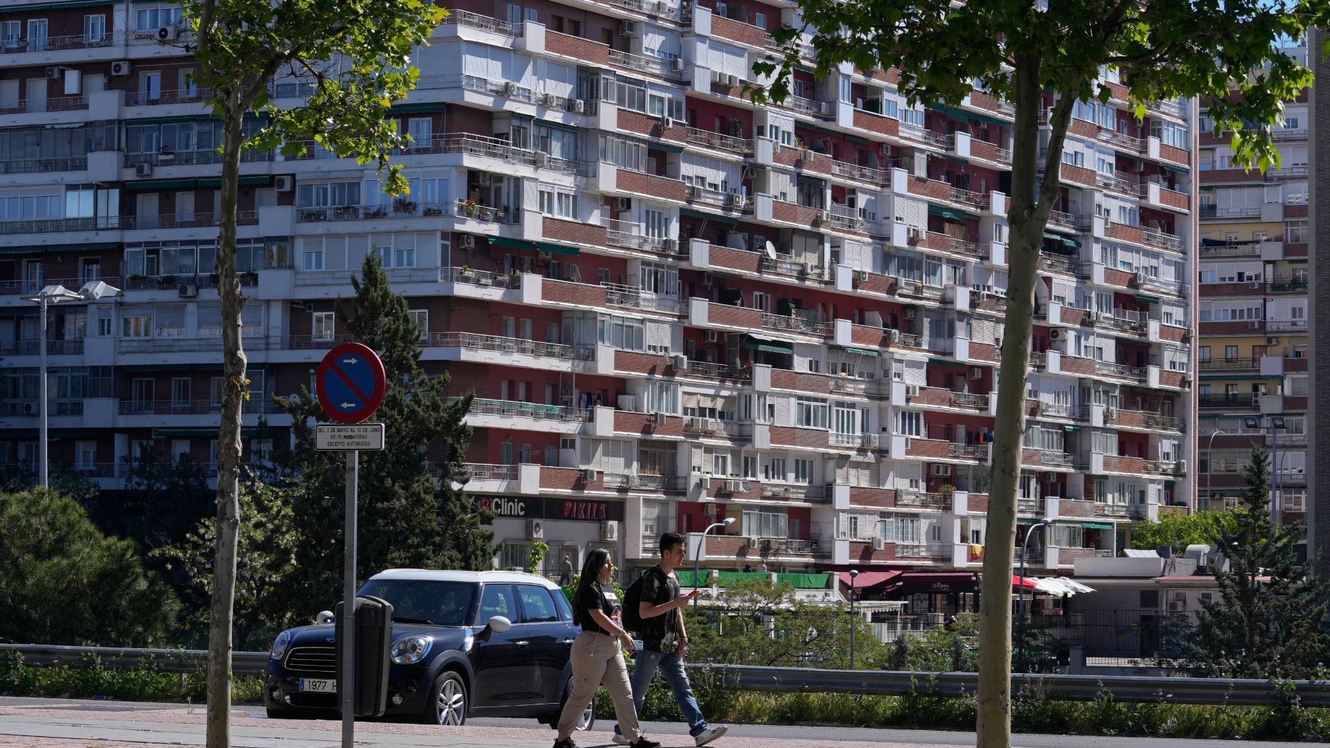 A young couple walk in front of housing blocks in Madrid. /Paul White/AP