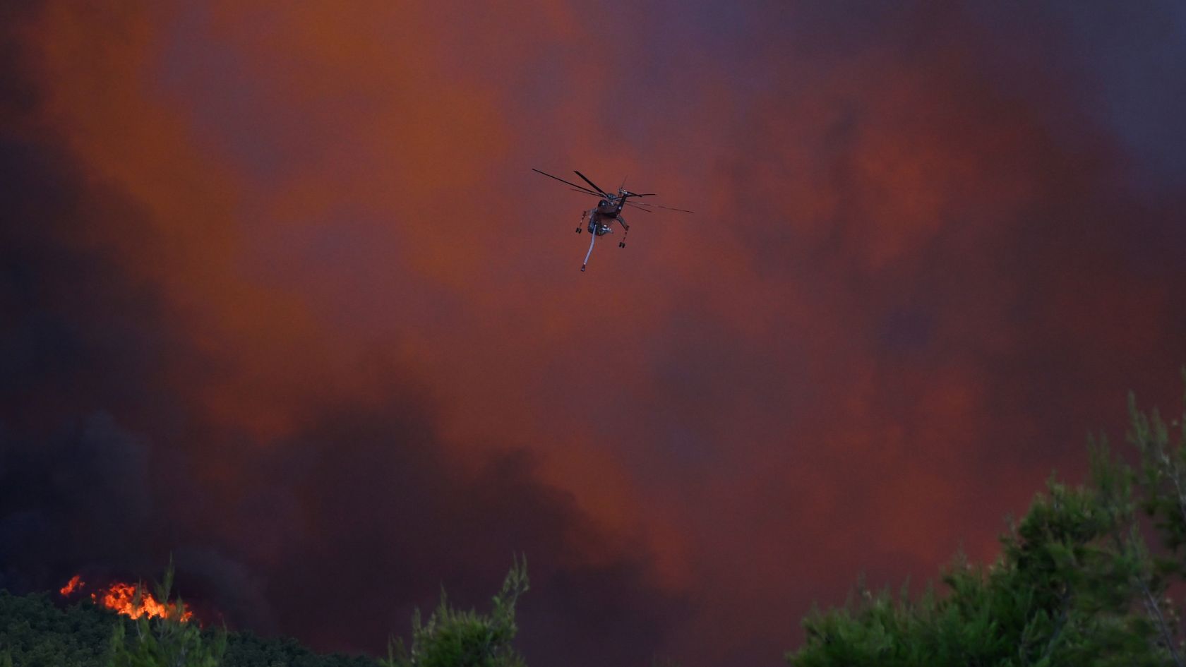 A firefighting helicopter flies amid heavy smoke, near Porto Germeno, northwest of Athens. /AP.
