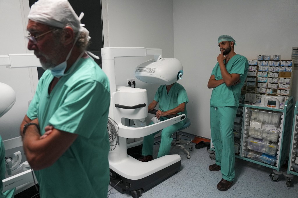 Sasha Stamenkovic (C) using the new Da Vinci 5 robotic-assisted surgical system while performing lung cancer surgery as Ali Ansaripour (R), senior cardiothoracic trainee on a robotic fellowship, looks on. /Carlos Jasso/AFP