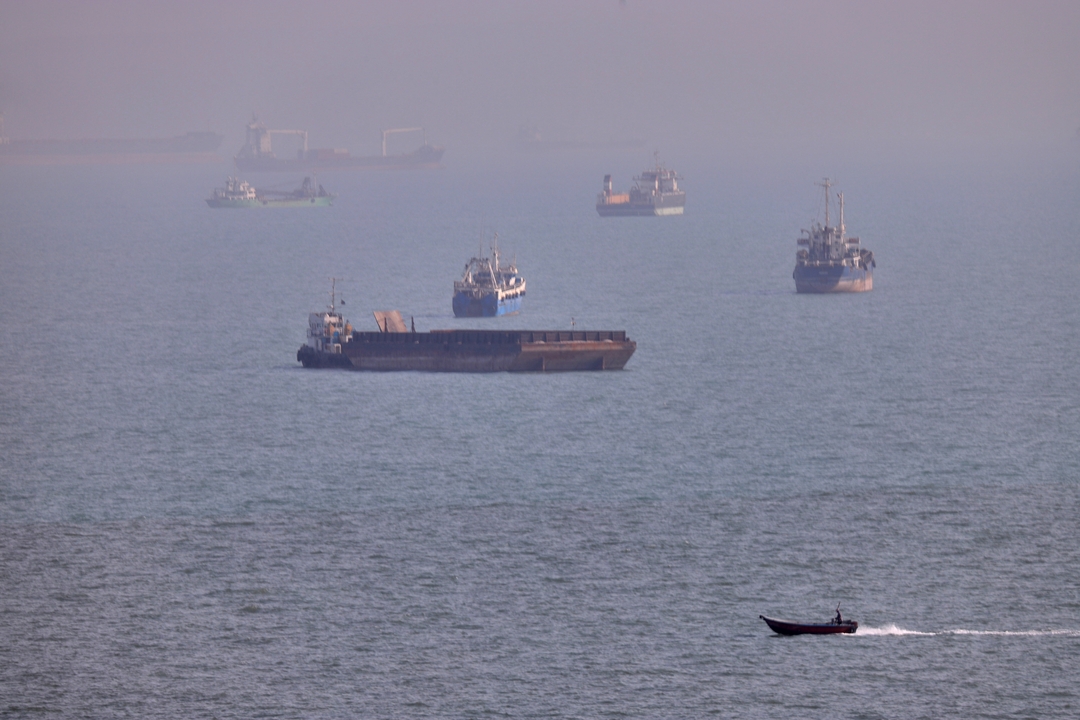 A small boat sails past cargo ships and other commercial vessels anchored in the Strait of Hormuz off Bandar Abbas, Iran, Wednesday, Aug. 5, 2026. /Amirhosein Khorgooi, ISNA via AP