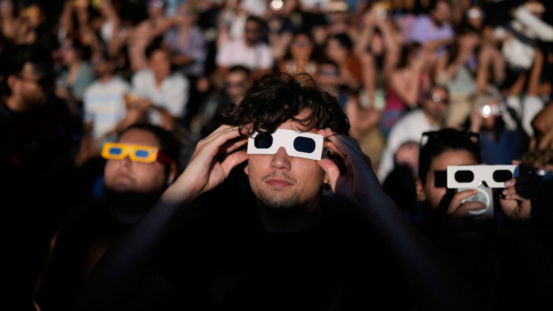 People gather at a viewpoint to watch the eclipse in Portugal's capital city, Lisbon. /Armando Franca/AP Photo