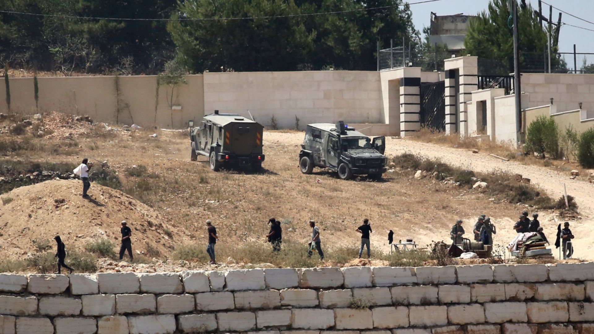 Israeli soldiers stand guard next to settlers in front of Palestinian homes that they have blockaded in the village of Qusra, south of Nablus, in the occupied West Bank, Wednesday, August 12, 2026. /Nidal Eshtayeh/AP