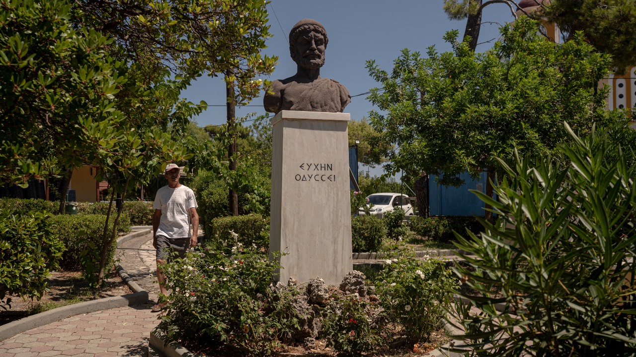 A man walks next to a bust of Odysseus in the central square of the village of Stavros, on the island of Ithaca. /Angelos Tzortzinis/AFP