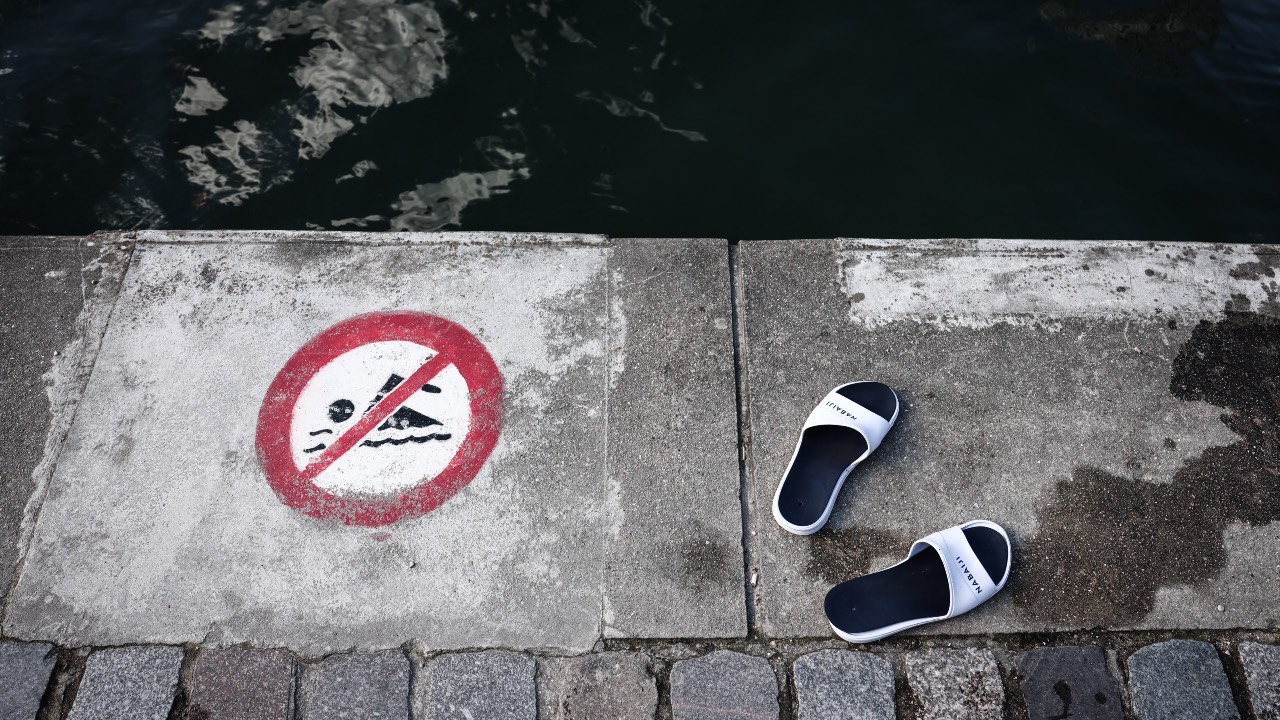 This photograph shows sandals next to a sign indicating that swimming is forbidden, at the Bassin de la Villette during a cold water swimming event in Paris on March 29, 2025. /Thibaud Moritz/AFP