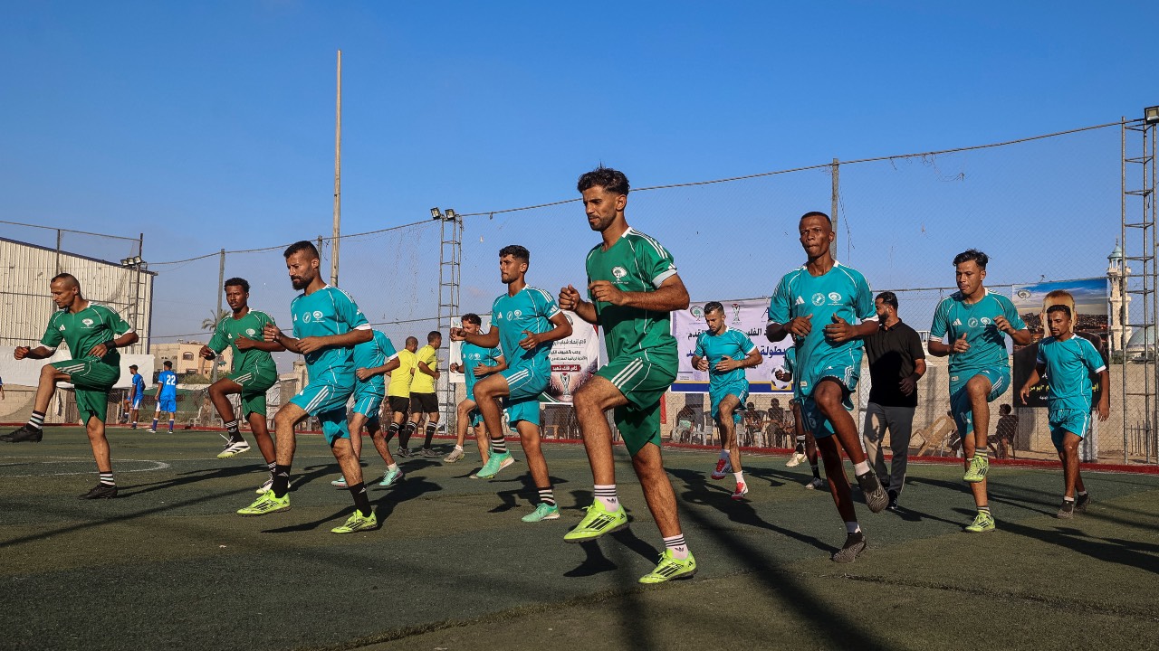 Khadamat Rafah team players warm up for their opening match against Shabab Rafah team in the Thousand Martyrs' Cup football tournament, in Deir el-Balah, central Gaza Strip. /Eyad Baba/AFP