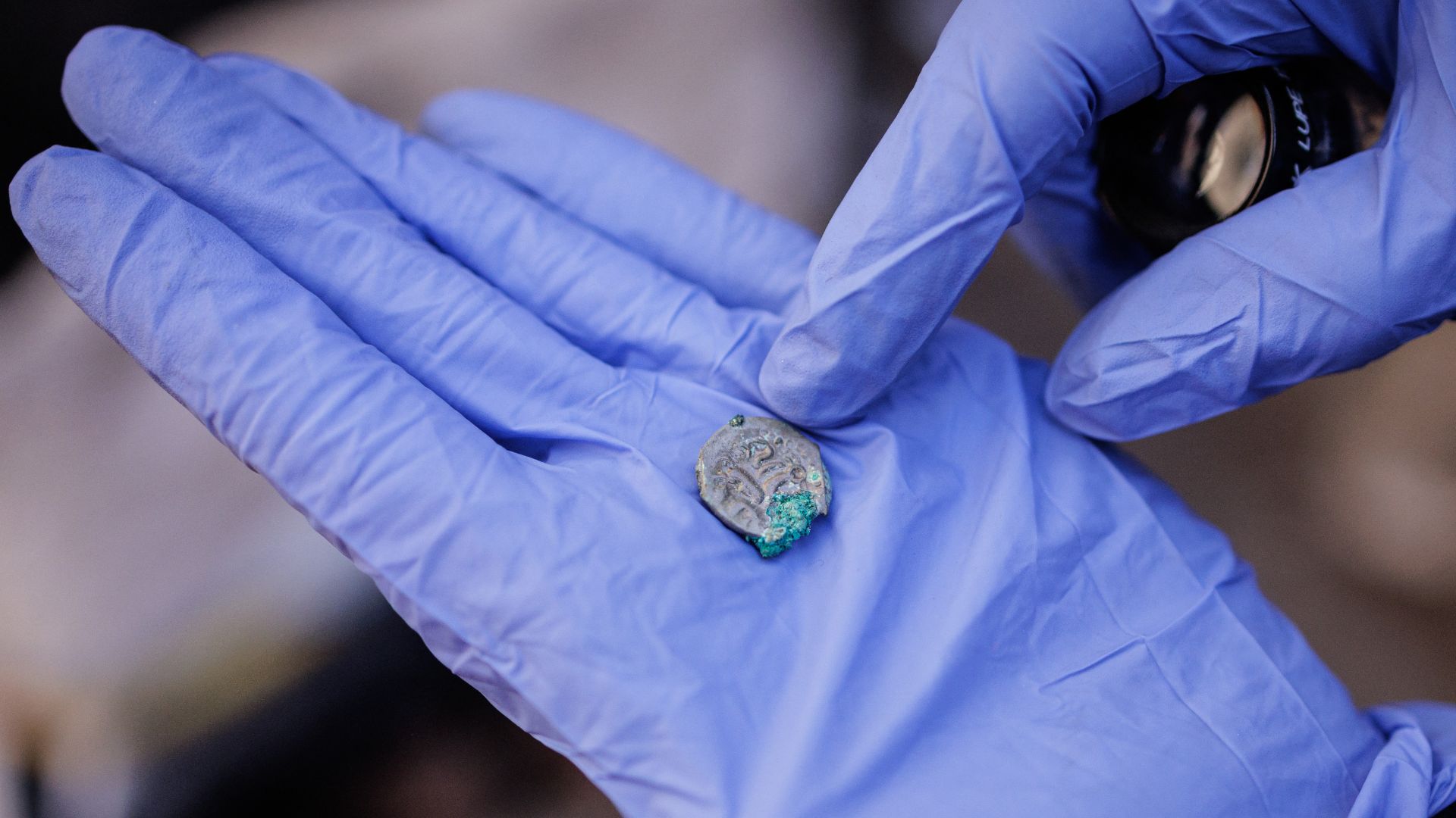 An archeologist for the city of Paris holds a Gallic coin during excavations at the archeological site. /Simon Wohlfahrt/AFP
