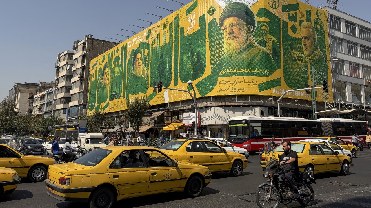 Iranians commute past a billboard depicting former Lebanese Hezbollah leader Hassan Nasrallah and Iran's former supreme leader Ayatollah Ali Khamenei in Tehran on the second anniversary of Nasrallah's killing in a major strike by Israel on Beirut's southern suburbs. /Atta Kenare/AFP