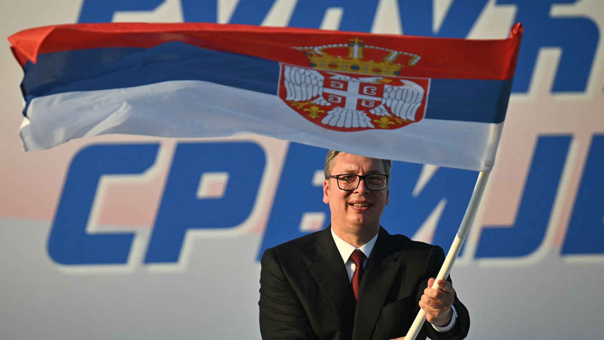  Serbia's President Aleksandar Vucic waves a Serbian flag during a rally in Belgrade in June. /Oliver Bunic/AFP

