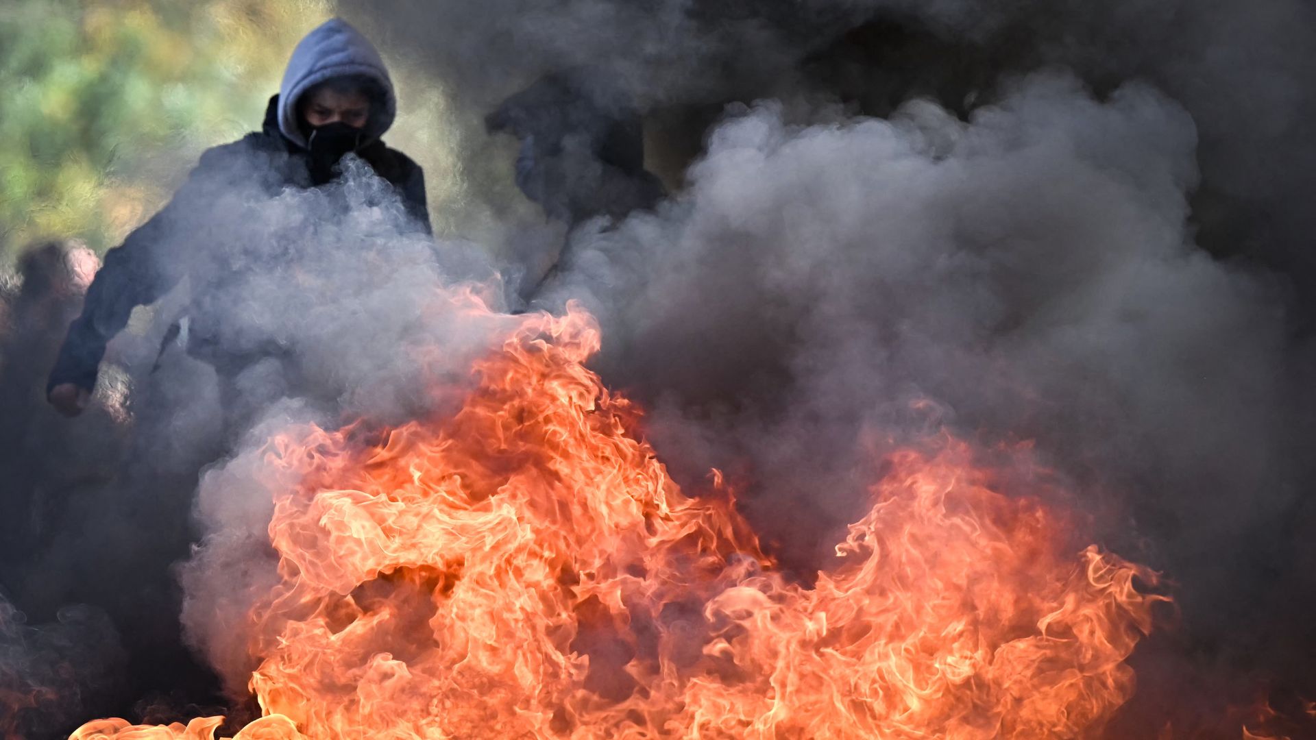 A protester stands next to the fire of a burning barrier as students take part in a blockading action outside the secondary school Le Corbusier, in Aubervilliers, northern Paris on Thursday. /Lou Benoist/AFP