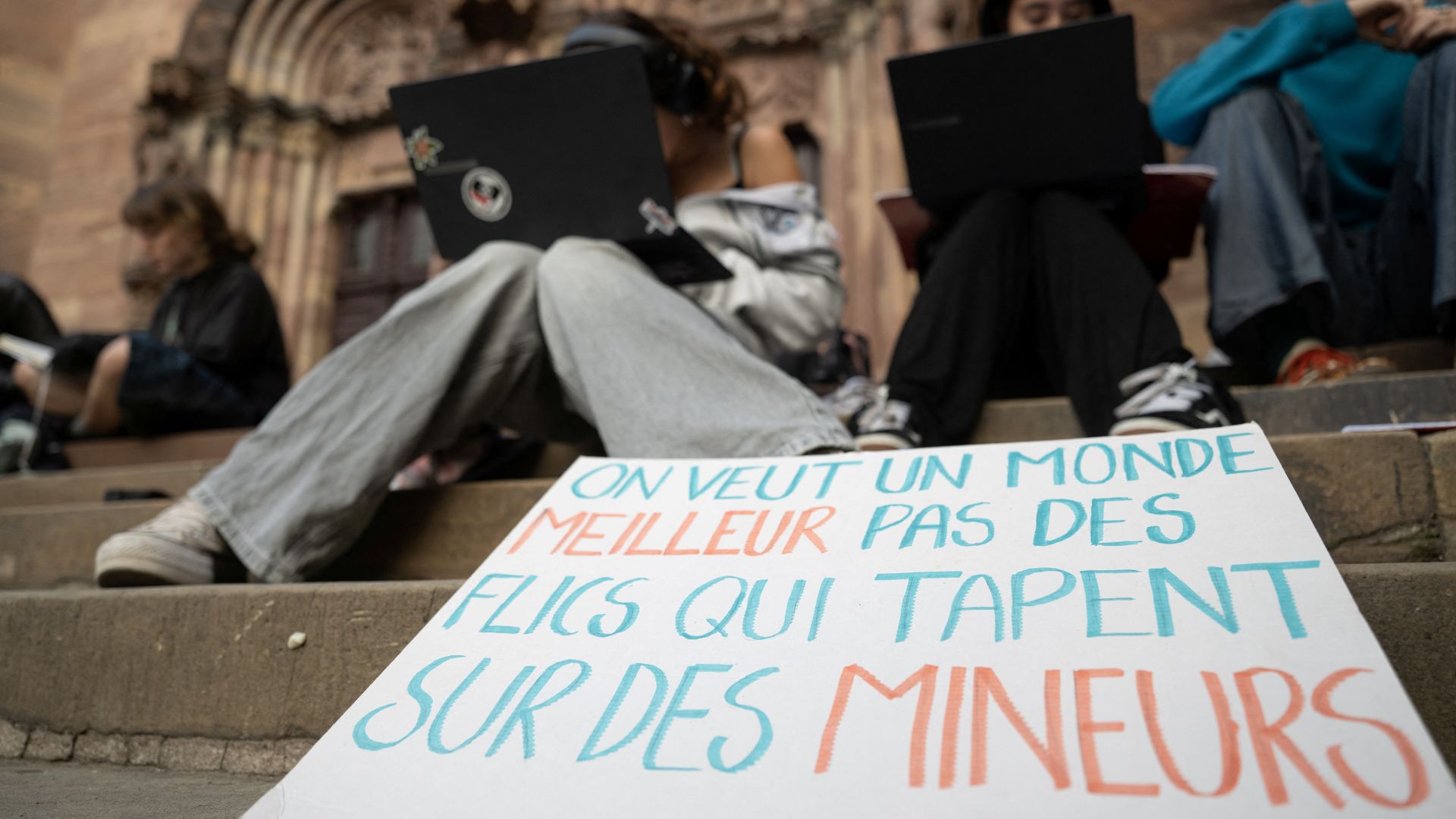 A student placard reading 'We want a better world, not cops beating up minors' as students work outside the closed Fustel de Coulanges secondary school in Strasbourg. /Sebastien Bozon/AFP
