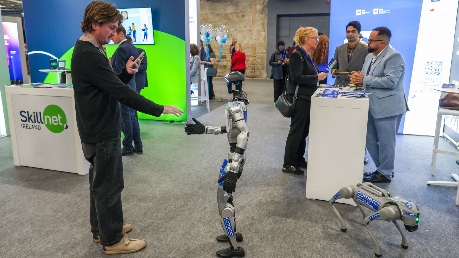 A Unitree G1 Humanoid agent AI avatar robot and a Go2 Quadruped Robot Dog at the International AI Summit. /Paul Faith/AFP

