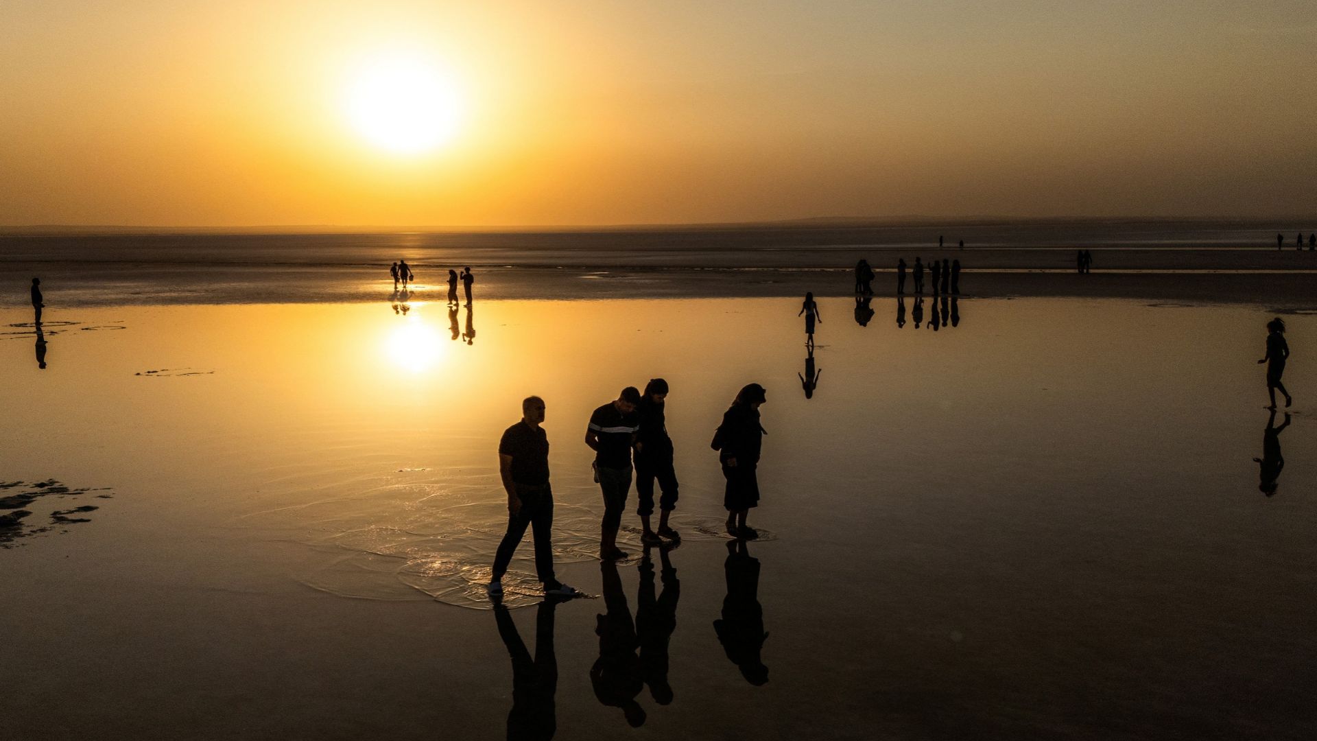Visitors walk on the reflective surface of the salt lake. /Ozan Kose/AFP
