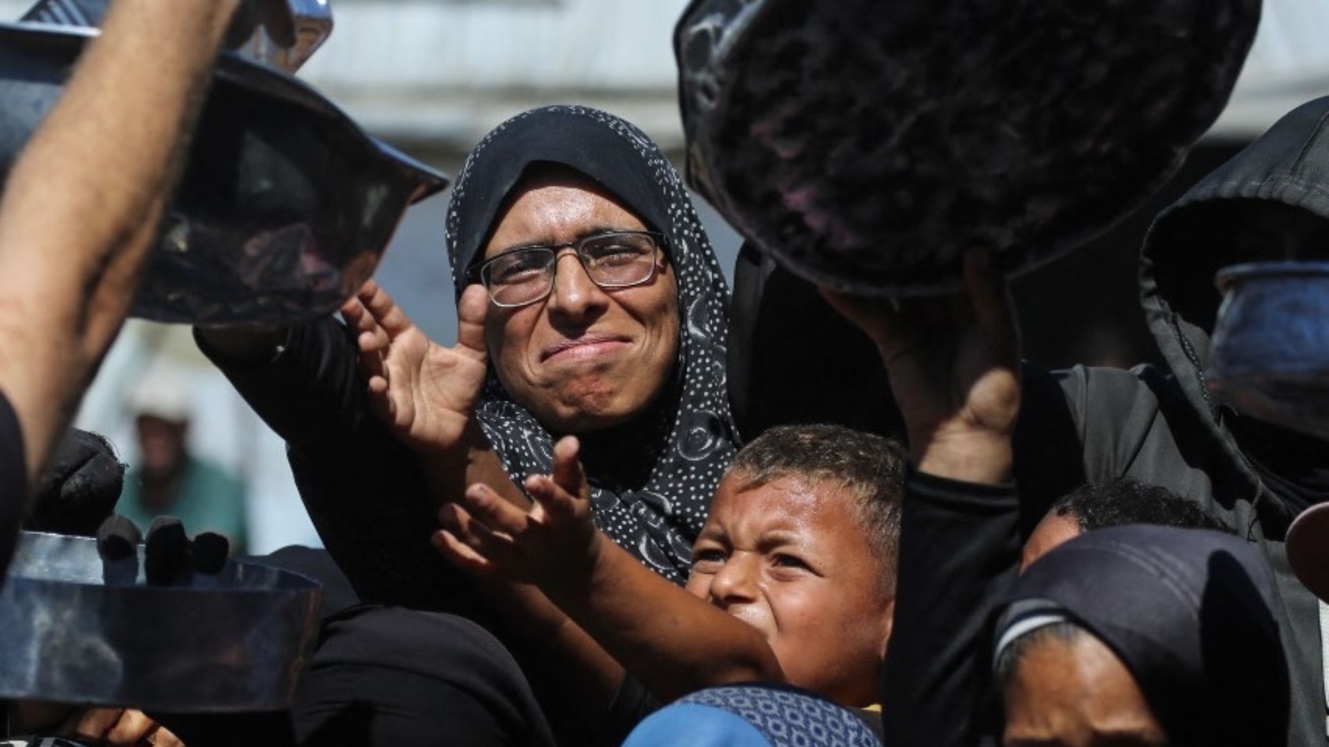 Nihaya Al-Masri, a 35-year-old displaced Palestinian woman from Beit Hanoun, waiting to receive food for her family at a charity kitchen in Khan Yunis, in the southern Gaza Strip. /Bashar Taleb/AFP