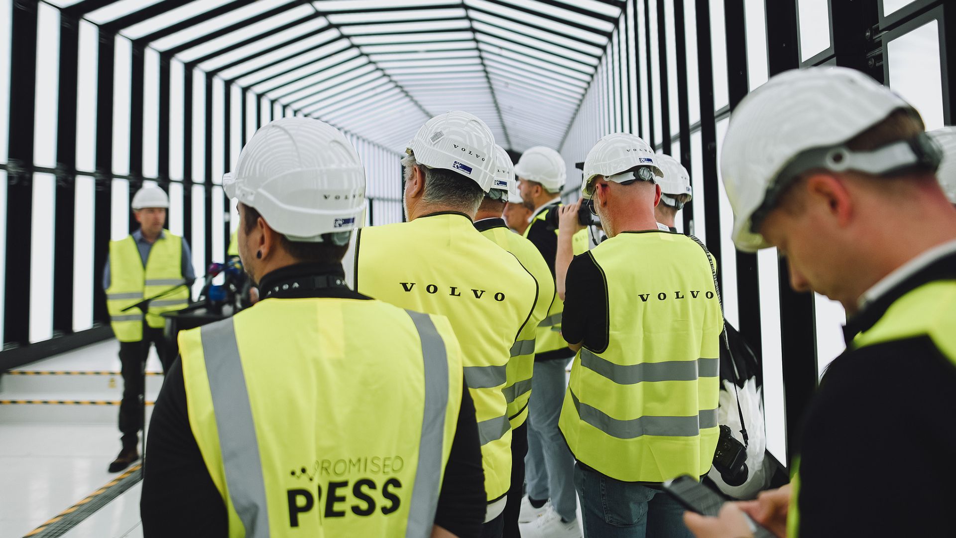 Workers dressed in Volvo branded clothing and wearing hard hats listen to opening remarks at a media day event at its new electric vehicle plant, alongside journalists. /Robert Nemeti/Getty Images