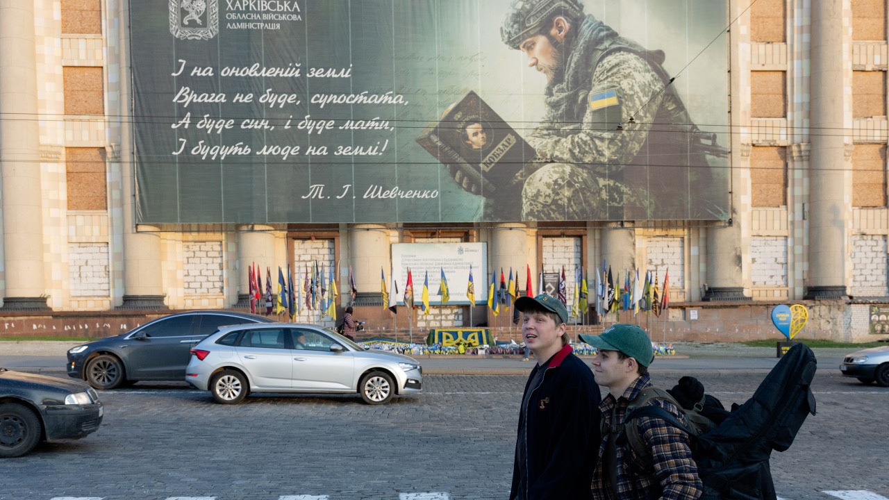 Boys walks past the damaged Kharkiv City and Regional Administration building in Kharkiv. /Tetiana Dzhafarova/AFP