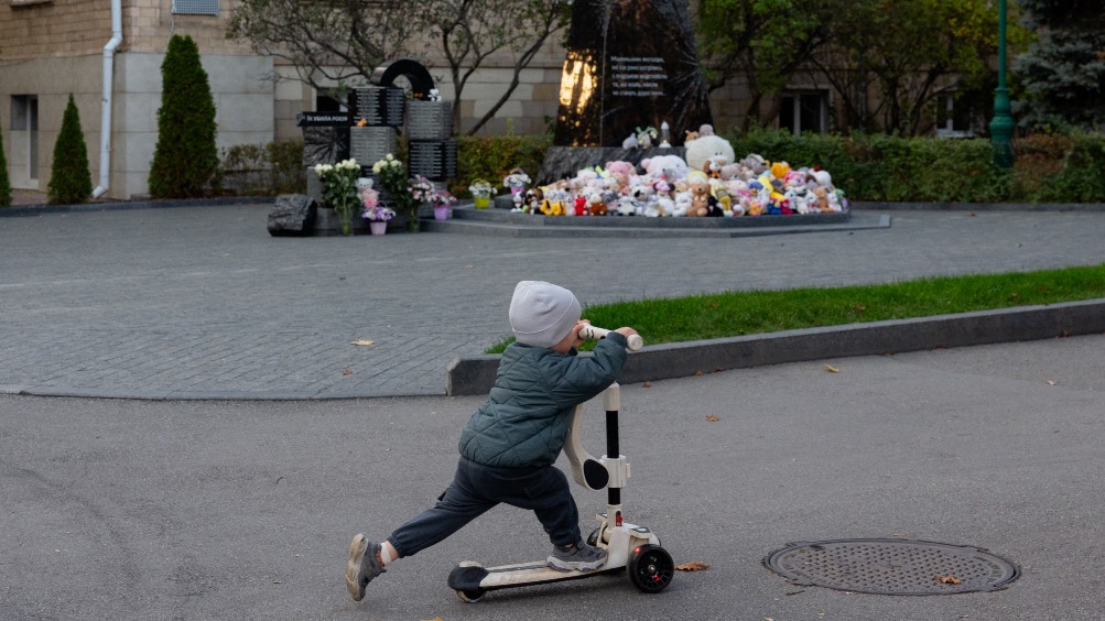 A boy riding a scooter near the monument to the children who died amid the conflict in Ukraine, in Kharkiv. /Tetiana Dzhafarova/AFP